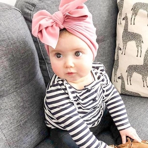 Dettaglio di un cappello a turbante rosa per neonati con un grande fiocco decorativo