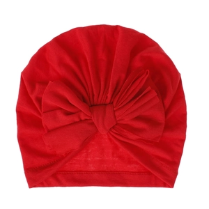 Dettaglio del cappello turbante rosso per neonato con un grande fiocco in maglia