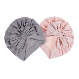 Dettaglio di turbanti per neonati in cotone morbido grigio e rosa con grandi fiocchi decorati