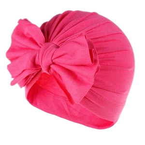 Primo piano di un turbante in cotone rosa per neonati con un grande fiocco decorativo