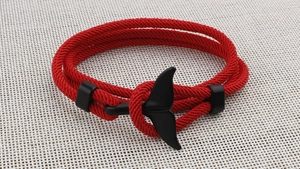Close-up of a red woven Milan cord bracelet with a matte black whale tail metal clasp