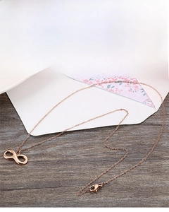 Macro view of rose gold infinity symbol necklace with fine chain on wooden surface