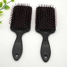 Top view of two professional black hairbrushes with red-tipped metal pins on white background