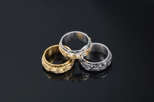 Close-up of three punk style dragon spinner rings in gold, silver, and dual-tone finish