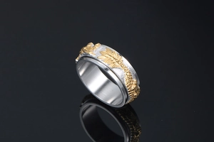Macro detail of rotating stainless steel spinner ring with golden dragon relief