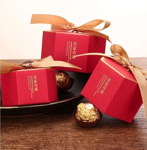 Detail of red hexagonal wedding gift boxes with gold ribbon bows and foil lettering