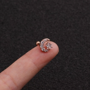 Rose gold moon and star cartilage earring with sparkling crystals held on a fingertip