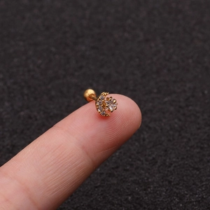 Macro shot of a gold moon and star cartilage earring with clear zircons on a fingertip