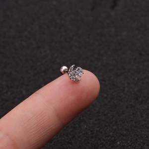 Macro view of silver crescent moon and star tragus stud with zircon on fingertip