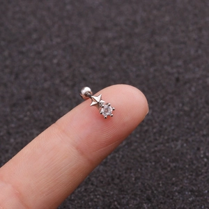 Close-up of a silver star-shaped cartilage stud with a clear zircon held by fingers