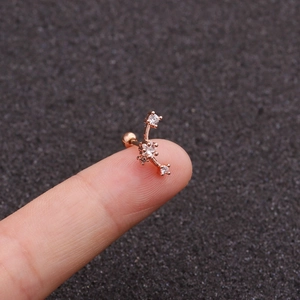 Close-up of rose gold crescent moon ear stud with zircons held by a hand on dark fabric