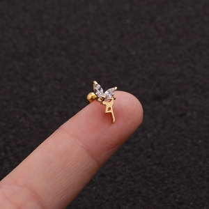 Dettaglio macro di un orecchino a geco dorato con zirconi marquis sulla punta del dito