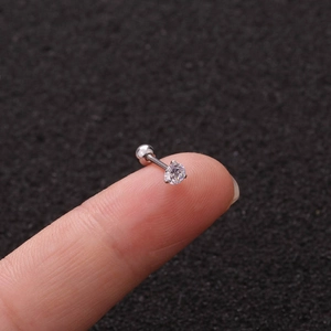 Macro di un piccolo orecchino in acciaio argentato con zircone sulla punta delle dita