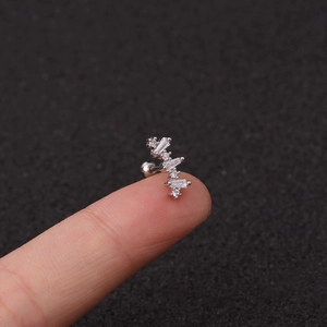 Macro detail of silver flower stud earring with sparkling rectangular zircons on finger