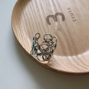 Detail of silver hollow chain ring on wooden tray with natural side lighting
