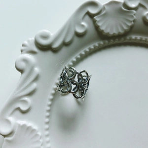 Detailed macro view of minimalist 925 sterling silver hollow intertwined ring on ceramic tray