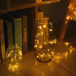 Warm yellow LED copper wire string lights in a glass vase for cozy home decor
