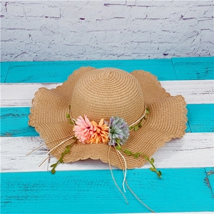Summer wide brim straw sun hat with floral accents and wavy edge for beach vacations
