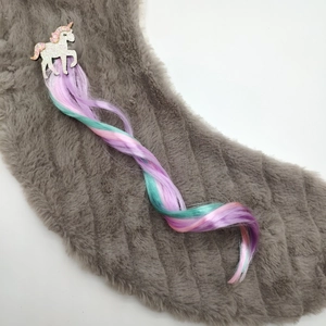 Close-up of a glitter unicorn hair clip with long colorful gradient curly hair extensions