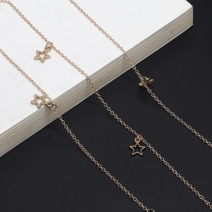 Detailed view of bronze star pendants on a metallic eyewear chain over a book