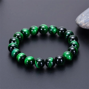 Macro shot of natural green tiger eye beaded bracelet showing cat-eye effect on black background
