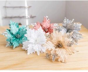 Glitter velvet Christmas flowers in five colors displayed on light wood surface
