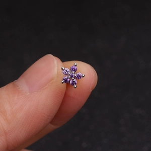 Minimalist stainless steel flower ear stud with purple crystal held by fingers