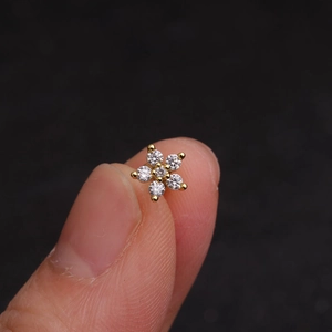 Macro shot of gold floral cartilage stud earring with inlaid sparkling crystals