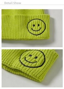 Close-up of neon green ribbed knit beanie with black embroidered smiley face detail