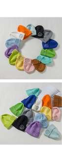 Detailed view of colorful knitted beanie caps with embroidered smiley face patches