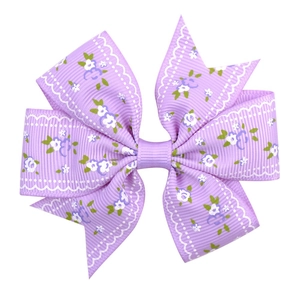 Detailed close-up of a purple floral bow hair clip featuring white daisy patterns