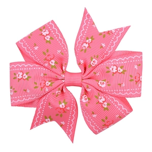 Detailed view of pink ribbon bow hair clip with white floral prints and lace edges