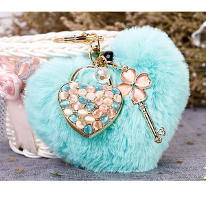 Detail of mint green plush heart keychain with gold heart lock and clover key pendant