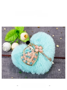 Detailed view of heart-shaped key pendant with pink opals and blue plush pompom