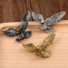 Detailed view of three eagle brooches in gold, silver, and bronze with red gemstone eyes
