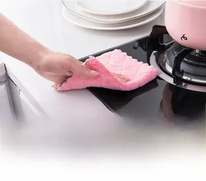 Close-up of hand using a waffle-textured microfiber cloth to clean a kitchen stove surface