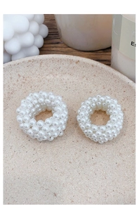 Detailed close-up of woven white faux pearl hair ties on a ceramic plate decor