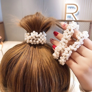 Close-up of a white pearl elastic hair tie used as a bracelet on a woman wrist