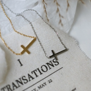 Macro view of gold and silver sideways cross necklaces on textured white fabric