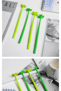 Detail view of four-leaf clover pens on a desk with a notebook and white ceramic mug