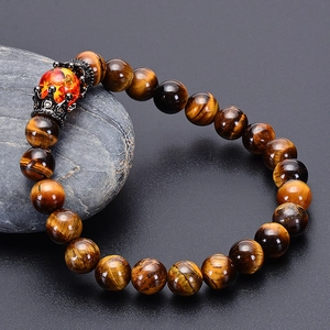 Natural tiger eye bead bracelet with black hollow crown charm on dark pebble stones