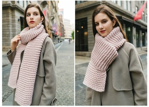Street style view of a pink thick-knit scarf with a cozy handmade texture on a model