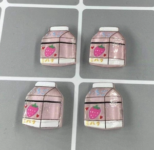 Detailed view of four mini pink strawberry milk box resin charms for DIY phone cases