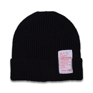 Detailed close-up of a black ribbed knit beanie featuring a vintage white textile label