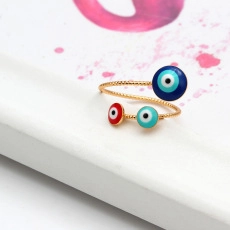 Detailed view of golden twisted ring with colorful evil eye charms in blue and red
