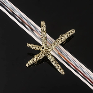 Close-up of a golden starfish hair clip with realistic honeycomb texture on black background