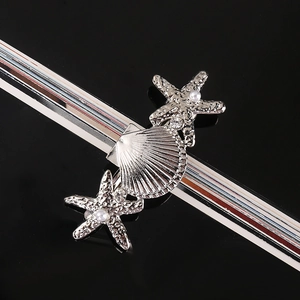 Detail of starfish and shell hair clip with pearls and rhinestones on black background