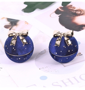 Detail of navy blue velvet sphere jewelry box with gold bow and starry speckle finish