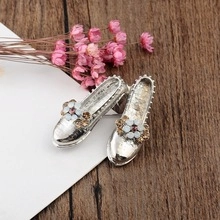 Close-up of miniature silver high-heeled shoes with flower detail and rhinestones