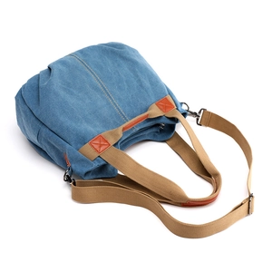Blue canvas tote bag with brown straps shown in a professional 45-degree overhead view